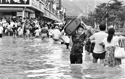 昨日，一名消防戰(zhàn)士在秦皇島市山海關(guān)火車站站前廣場涉水幫助旅客運送行李。 新華社發(fā)