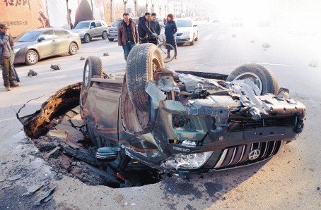 沈陽一道路現(xiàn)大坑 霸道車遭橫禍四腳朝天(圖)