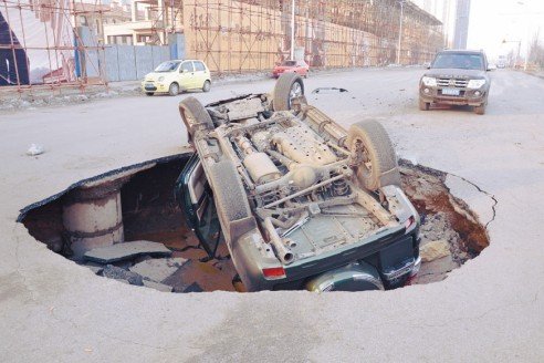 沈陽一道路現(xiàn)大坑 霸道車遭橫禍四腳朝天(圖)